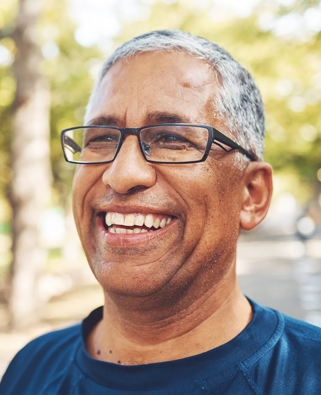 A smiling man in his late 50s with glasses, outdoors