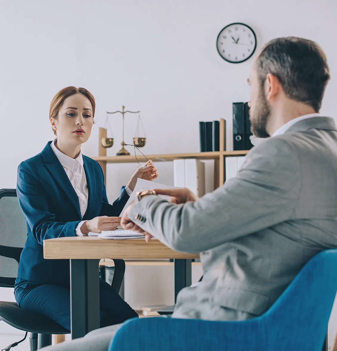 A lawyer reviews documents with a client across a desk in her office